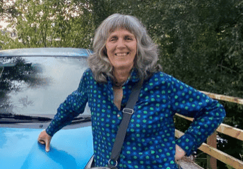 Alison standing next to blue car